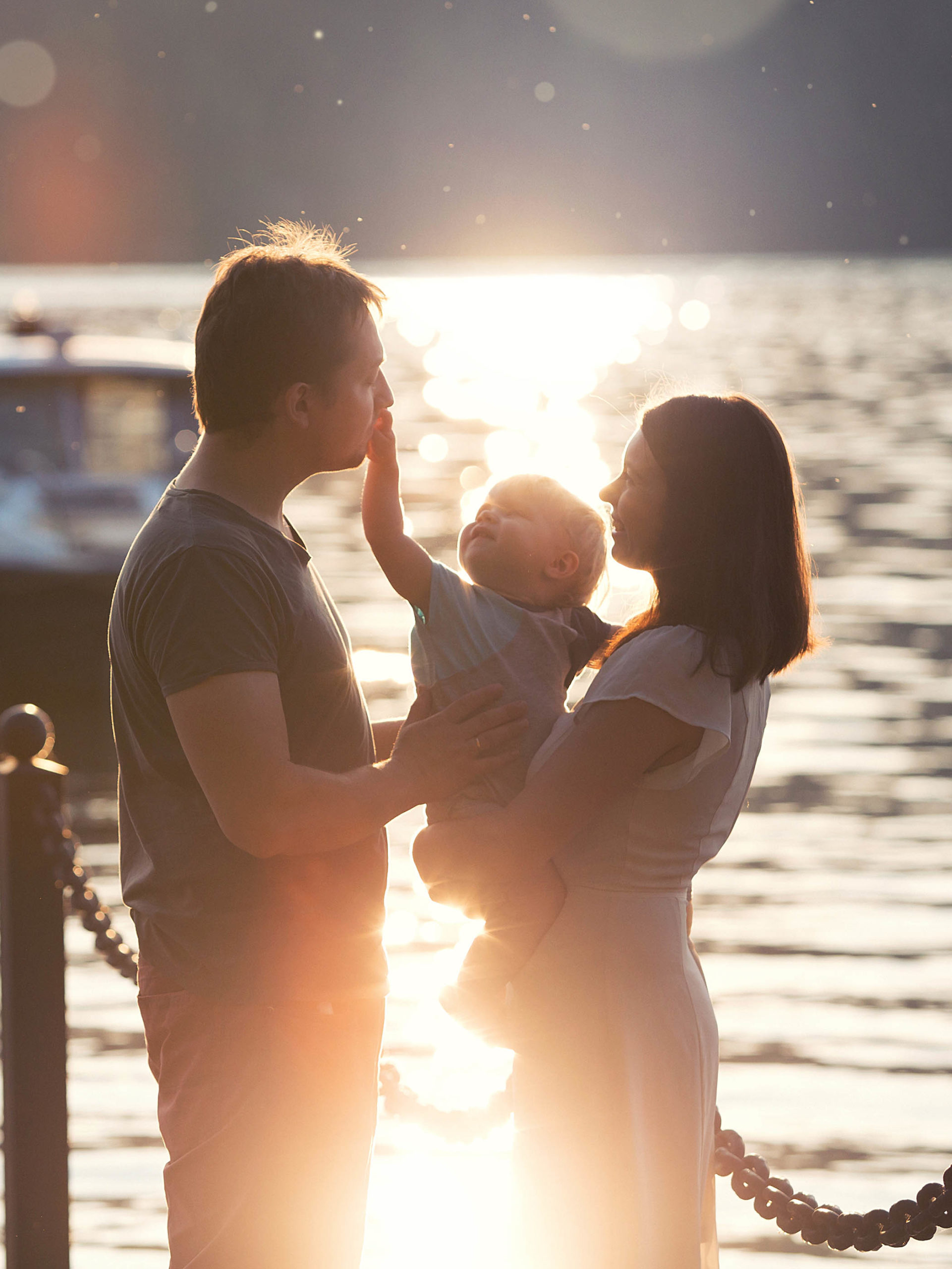 mom and dad and one-year-old son on the dock in a lake