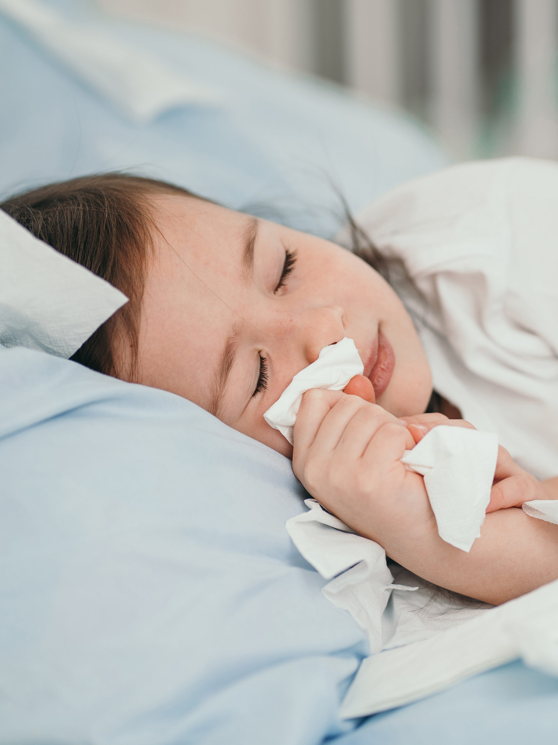 little girl with a cold wiping her nose with a tissue