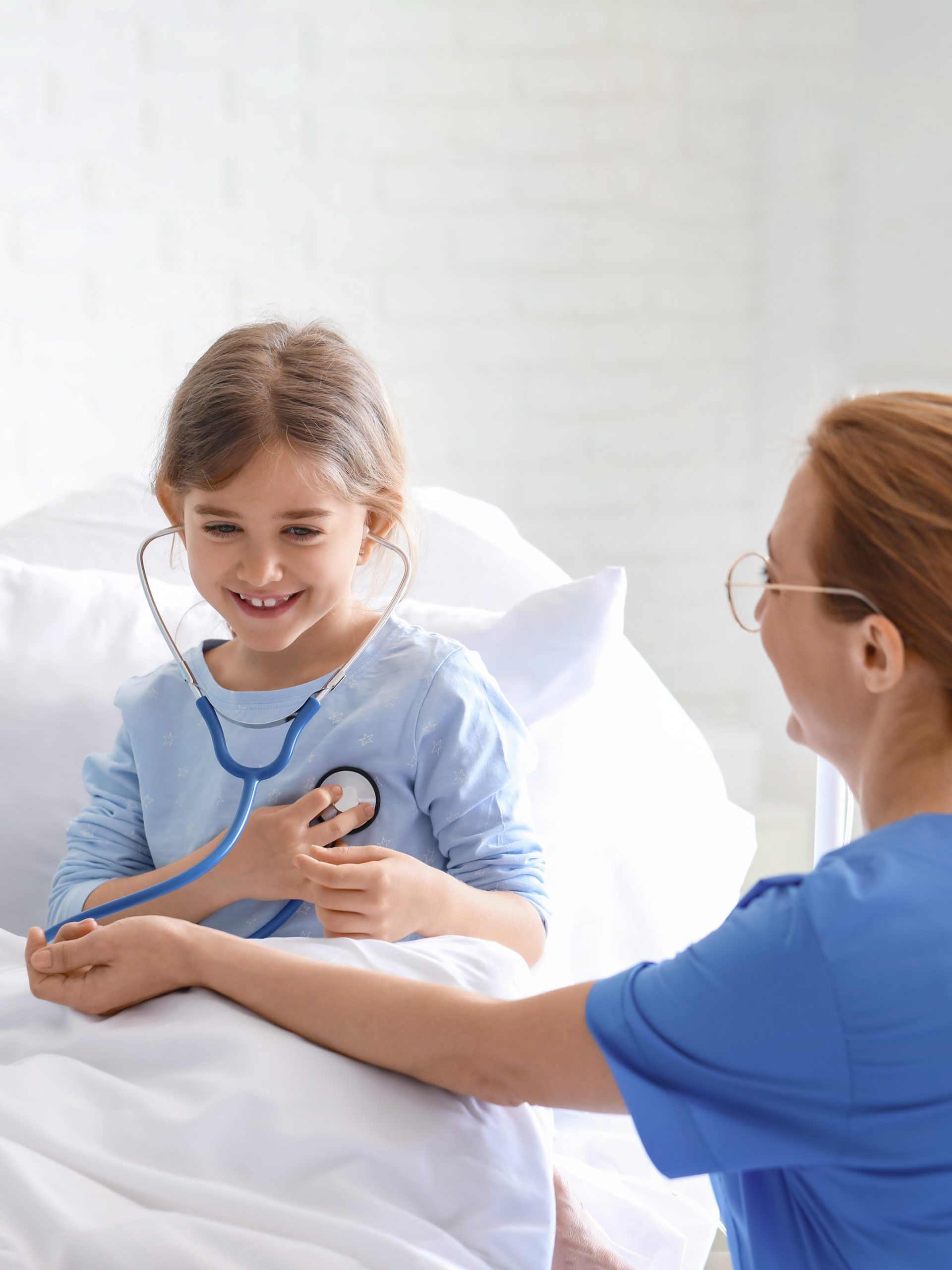 Female doctor working with little girl in hospital room