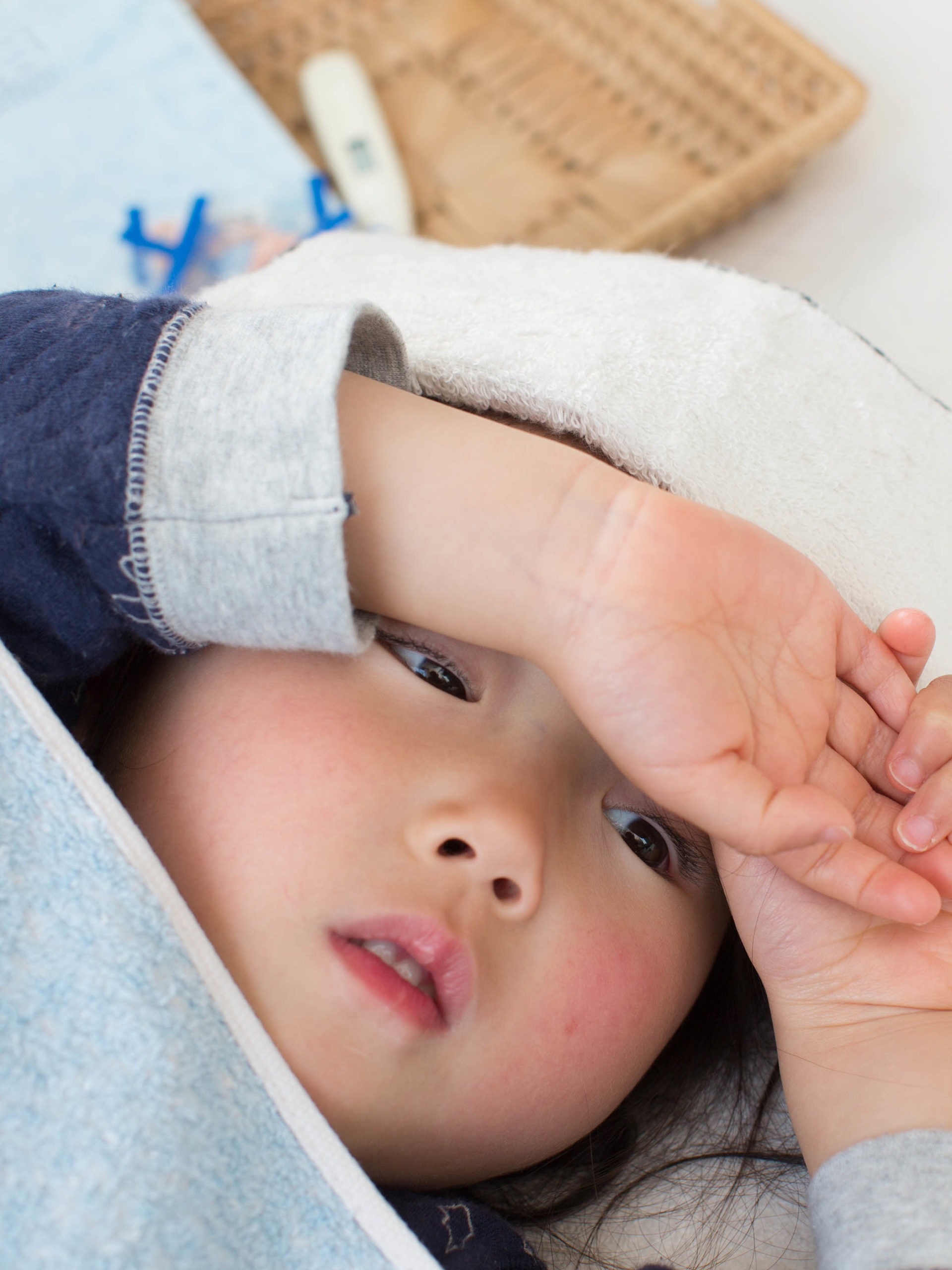 sick child lying down with a fever and a cool clother on her head