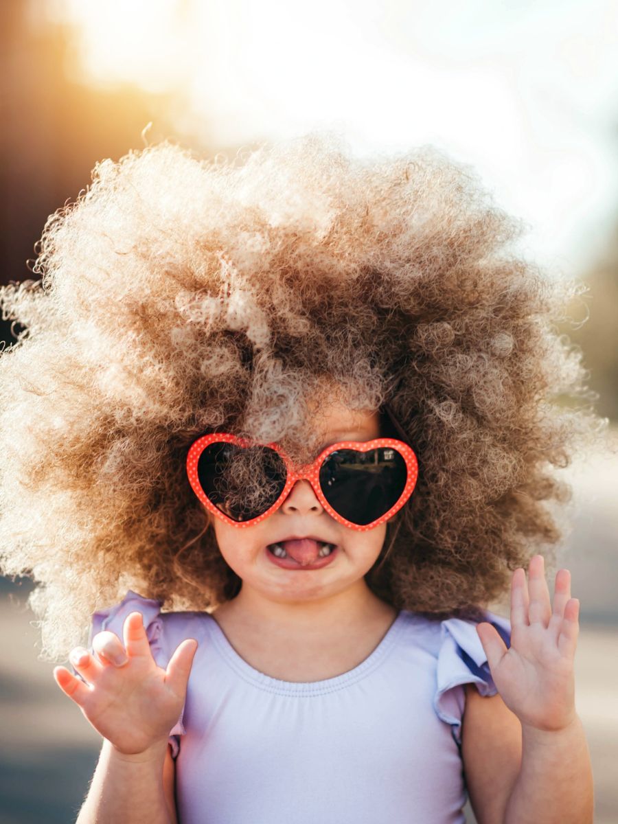 Little girl with heart shaped sunglasses sticking her tongue out